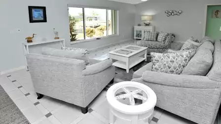 Bright living room with coastal accents, comfy sofas and a view of the garden and canal.