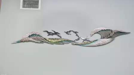 Wall sculpture with gulls, waves and starfish in a metallic finish adds coastal flair and motion to the living room.