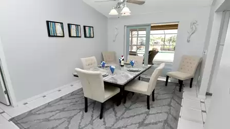 Modern dining area with elegant marble table, comfy upholstered chairs and access to the covered patio.