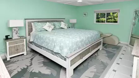 Coastal master bedroom with king-size bed, mint green tones and a view into lush tropical greenery.