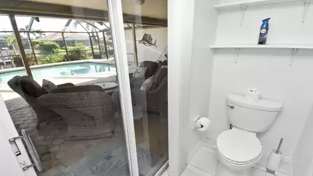 Toilet in the master bathroom with access to the patio and view of pool and canal