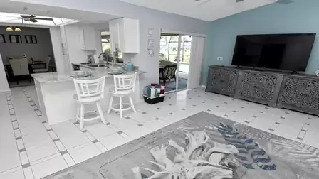 Open living space with kitchen bar, dining area view and access to the pool patio