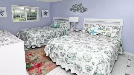 Coastal bedroom in pastel tones with two comfy full size beds and plenty of daylight