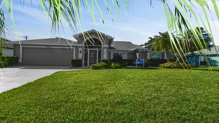 Villa Mei Jing in Cape Coral with a neat front yard, palm trees and tropical flair