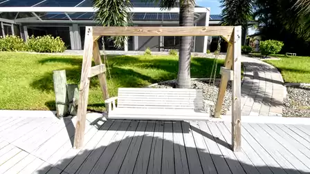White wooden swing by the dock – a spot for daydreaming, gently swaying in the warm breeze while gazing at the palms and the sparkling canal.