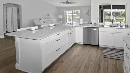 Modern, stylish all-white kitchen with spacious worktop and view of the second living room