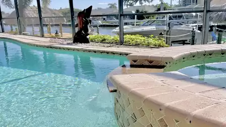Private pool area with waterfall, sun terrace and canal view with boat dock in a quiet waterfront setting.