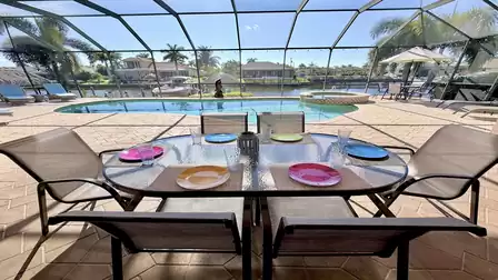 Covered dining area with table for six and overlooking the pool