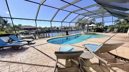 Spacious pool area with sun loungers, spa and screened patio offering open views of the canal.