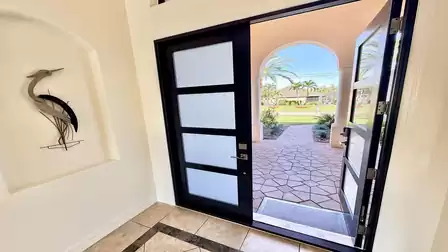 Open entrance area with modern front door, bright foyer and view through the archway to the well-kept front yard.