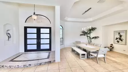 Light-filled dining area with high ceiling, large dining table and modern furnishings