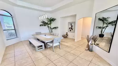 Elegant dining area with large table, modern lighting, high ceilings and an open, airy room layout.