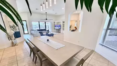 Open-plan living and dining area with large dining table, cozy sitting area, and plenty of natural light.