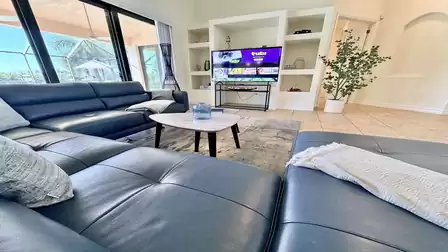 Modern living area with large leather sofa, TV, coffee table and views through sliding doors to the terrace.