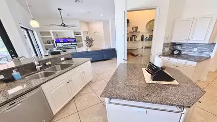 Modern open kitchen with island, granite countertops, ample storage and a direct view into the living area.