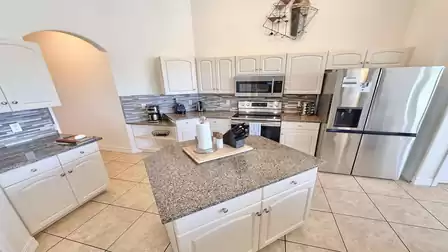 Bright kitchen with central island, granite countertops, stainless steel appliances and plenty of storage space.
