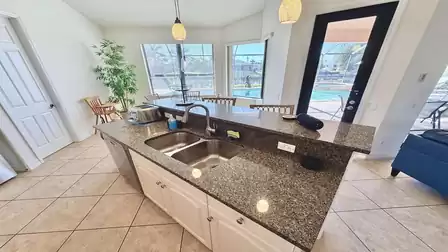 Kitchen island with double sink, granite countertop, breakfast bar and direct views to the pool and patio.