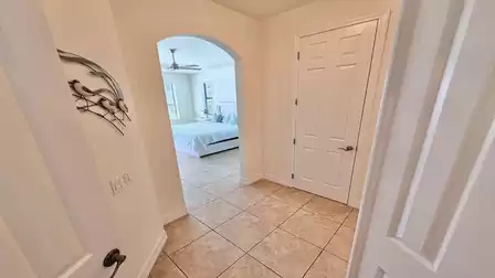 Bright hallway with arched doorway, view into the bedroom, light tile floors and a calm, welcoming atmosphere.