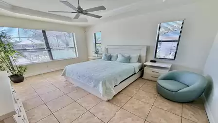 Bright bedroom with king-size bed, large windows, ceiling fan, and a calm canal view for relaxing stays.