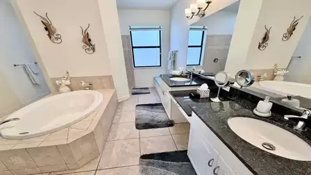 Modern bathroom with bathtub, double vanity, large mirror area, and a separate walk-in shower.