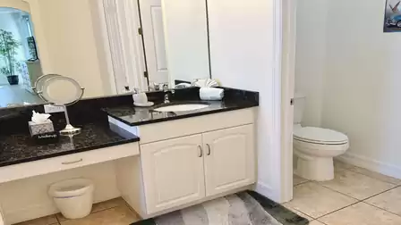 The master bathroom impresses with its combination of white furniture and black granite counters. 
