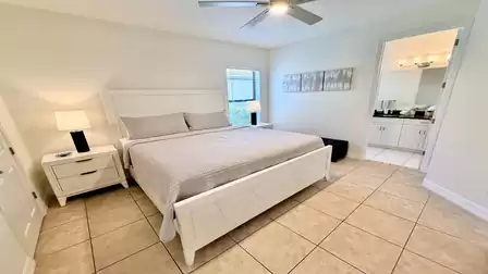 Calm bedroom with king size bed, nightstands, ceiling fan, and direct access to a modern bathroom.