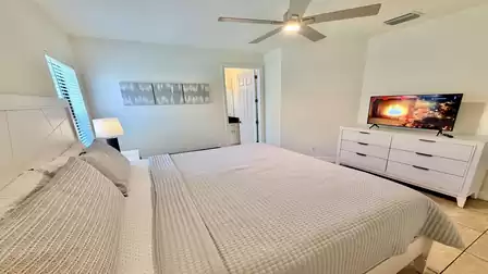 Bright bedroom with King size bed, TV, ceiling fan, and direct access to an en-suite bathroom.