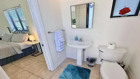 bathroom with pedestal sink, toilet, can also used as pool bath. View into the adjacent bedroom.