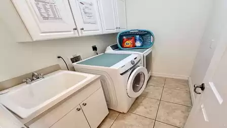 Laundry room with washer, dryer, utility sink and storage cabinets, ideal for longer stays.