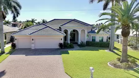 Exterior view of the vacation villa with palm garden, driveway and modern architecture in sunny weather.