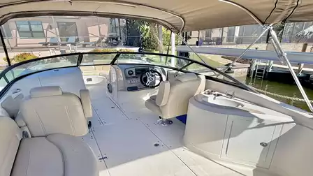 Motorboat cockpit with helm, seating area and sun canopy, moored at a private dock.