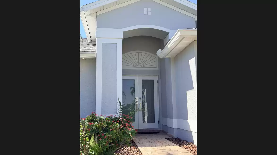 Entrance area with covered porch, bright front door and lush landscaping.