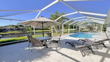 Large pool area inside the screen with seating, sun loungers and open views across the lake.