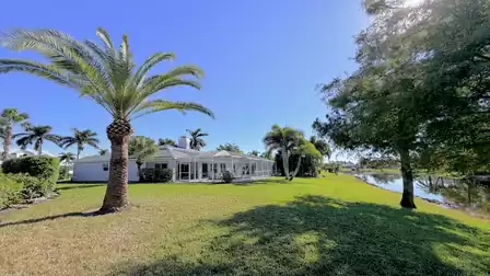 Garden view with palm trees, screen area and direct location on a peaceful lake behind the house.