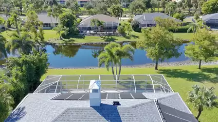 Aerial view overlooking the house, the screen enclosure and the calm lake behind the garden.