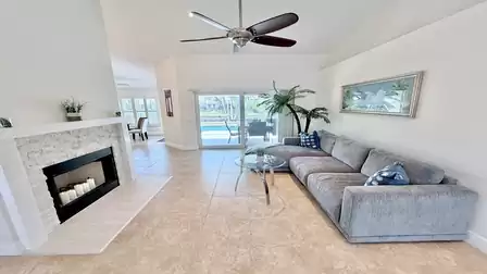 Living area with large sectional sofa, fireplace, ceiling fan and direct access to the pool area.