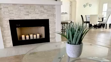 Close-up of the fireplace with candles in the living room, with the open dining area in the background.