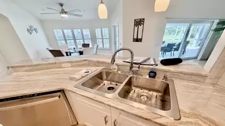 Kitchen countertop with double sink, modern faucet and view toward the dining area and terrace.