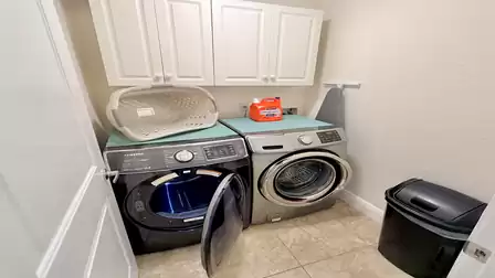 Laundry room with washer, dryer, storage cabinets and ironing board in a bright, practical layout.