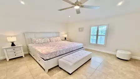 Master bedroom with Kingsize bed, decorated almost entirely in white.
