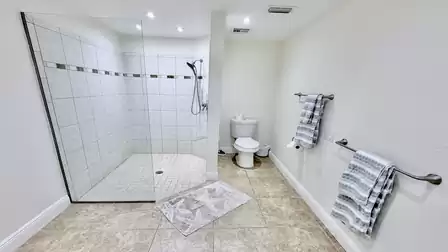 Large open shower with semi-glazed walls and toilet