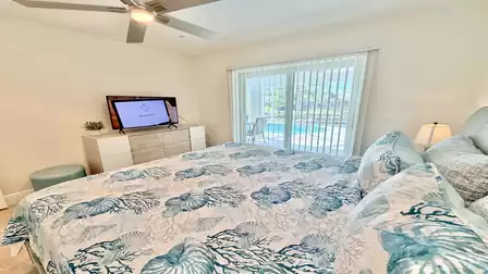 Bedroom with king-size bed, TV and direct view of the pool area through large sliding glass doors