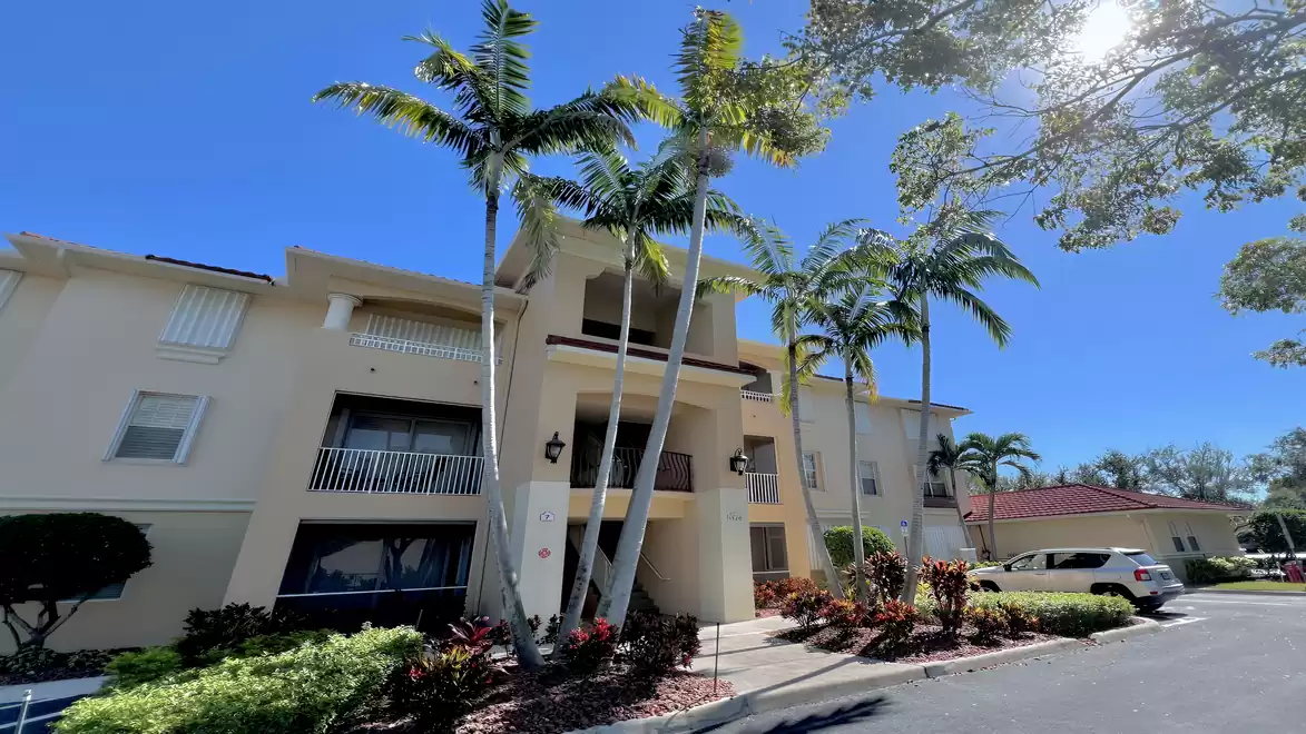 Exterior view of Condo Sunset at Porto Vista, surrounded by palm trees and well-kept tropical landscaping.