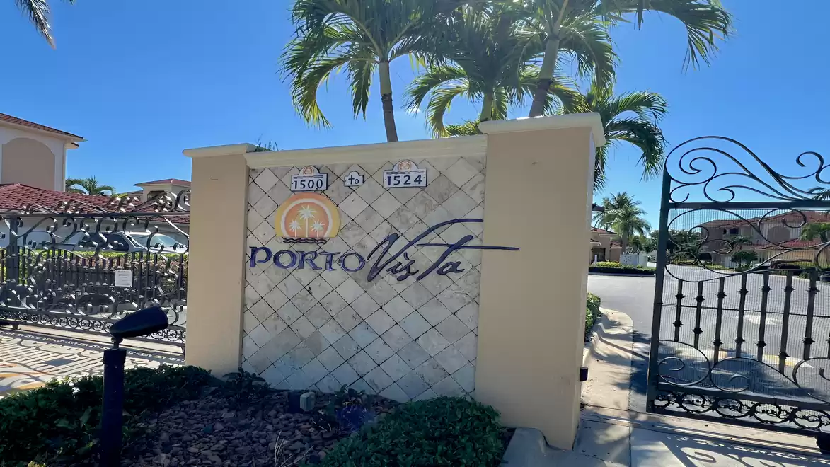 Gated entrance of the Porto Vista community with palm trees, logo and controlled access