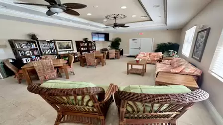 Bright community lounge with comfortable seating, tables, bookshelves and ceiling fans