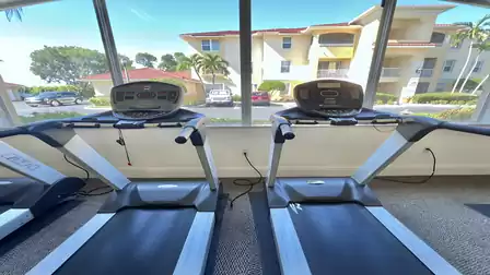 Fitness room with treadmills and large windows overlooking the residential area