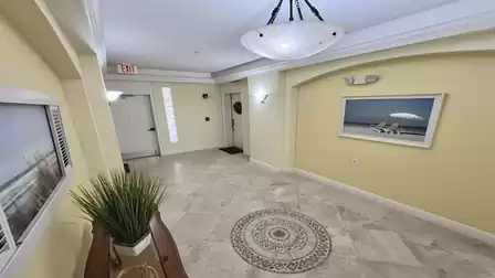Well-maintained building entrance with tiled floor, lighting, and apartment doors