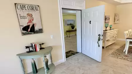Condo entry area with open front door, tiled floor, and coastal-style décor