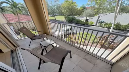 Covered balcony with seating and a view of the landscaped surroundings