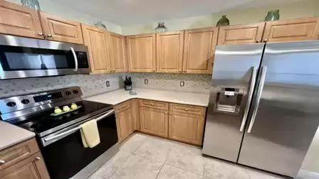 Fully equipped kitchen with wooden cabinets, stainless steel stove, microwave, refrigerator, dishwasher, and light-colored countertops.